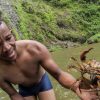 A man holding a crab in front of a Salto La Jalda (Hiking and Swimming).